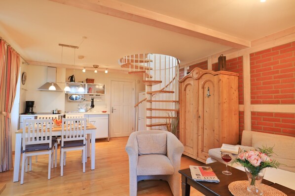 Un espacio habitable compacto con cocina, comedor y una escalera en espiral.
