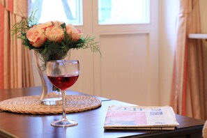 A glass of red wine, a bouquet of flowers, and a newspaper on a table.