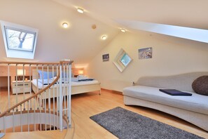 A bedroom with a bunk bed, a staircase, a sofa, and a skylight.