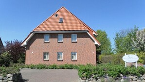 En bygning med røde mursten, et tag med teglsten, en belagt indgang og et skilt.