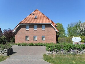 A red-brick building with a tiled roof, a paved entrance, and a signboard. - Haus Seepferdchen Whg. SP2 (Ostseebad Boltenhagen)