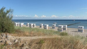 En strand med hvide strandhuse med skiltene V19, V27, V31 og V21.
