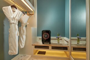 Bathroom features a large mirror, a bench with a small table, and two vases with flowers.