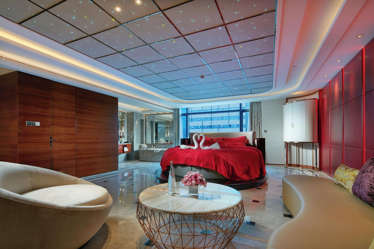 Ein modernes Hotelzimmer mit einem großen Bett, einem runden Couchtisch und einer Sitzecke.