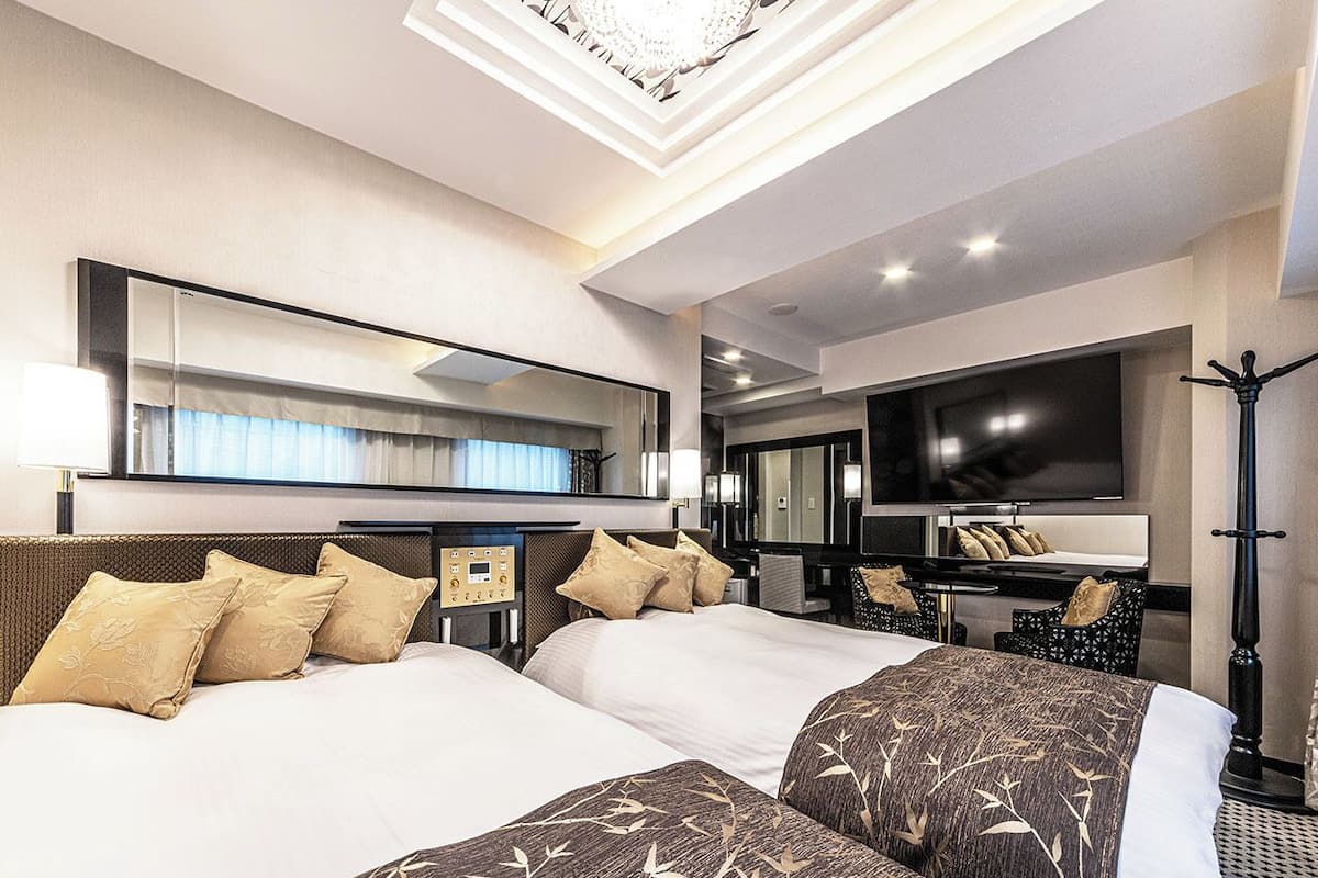 A hotel room with two beds, a large flat-screen TV, a desk, and a mirror.