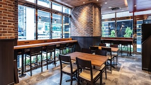 A modern restaurant interior with brick walls, large windows, and wooden tables and chairs. - APA HOTEL Roppongi Six (Tokyo)
