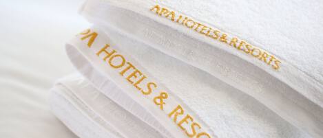 A stack of white towels with embroidered text reading "AAA HOTELS & RESORTS".