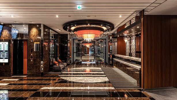 A modern hotel lobby with a marble floor, a central staircase, and a reception desk. - APA HOTEL Roppongi Six (Tokyo)