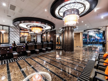 A modern lobby with a marble floor, a reception desk, and a large chandelier.. Apa Hotel Higashi Shinjuku Kabukicho Tower