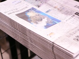 A stack of newspapers with a map and text on the front page.