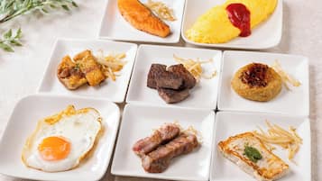 A variety of dishes including salmon, steak, and a fried egg, arranged on white square plates.