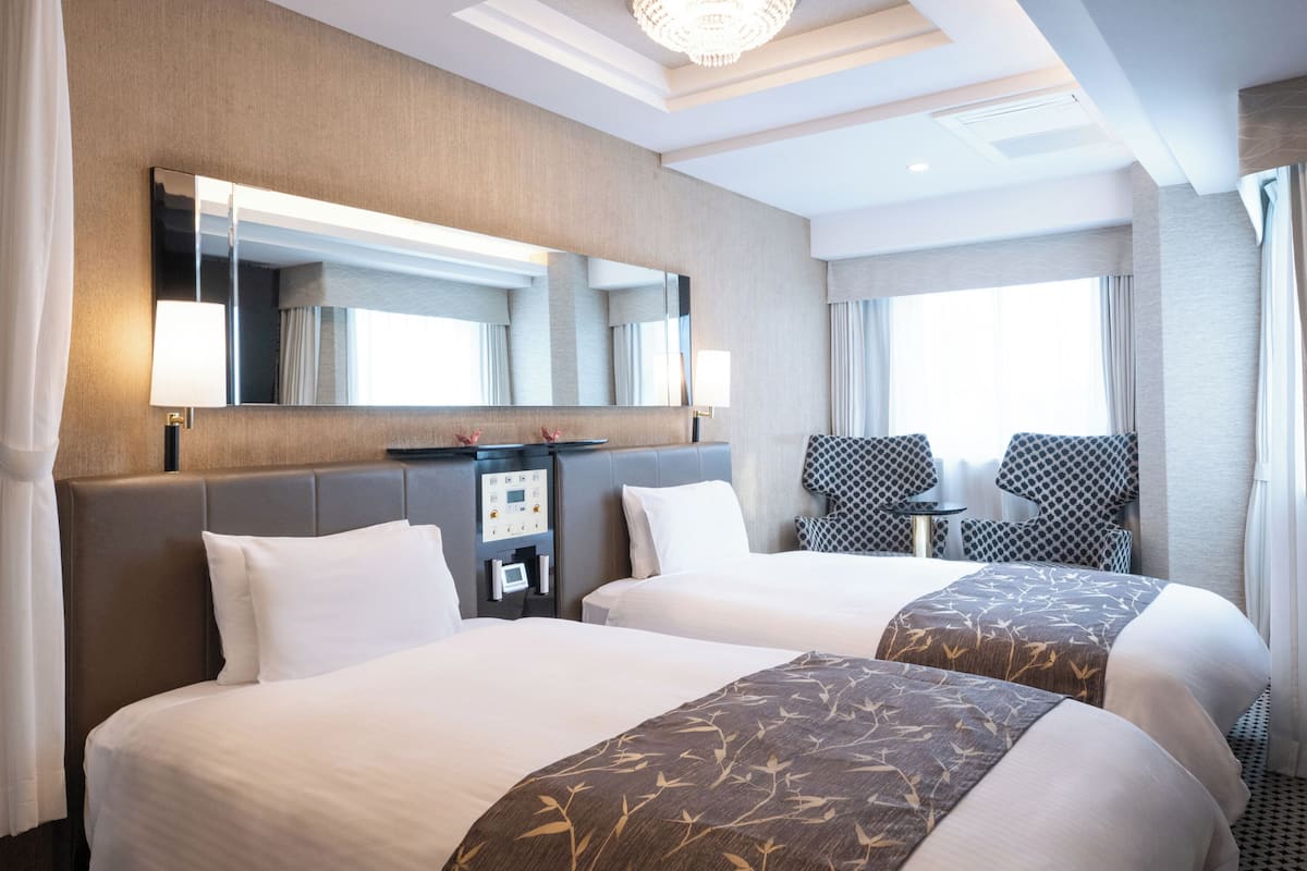 A hotel room with two beds, a large mirror, a desk, and a chair.