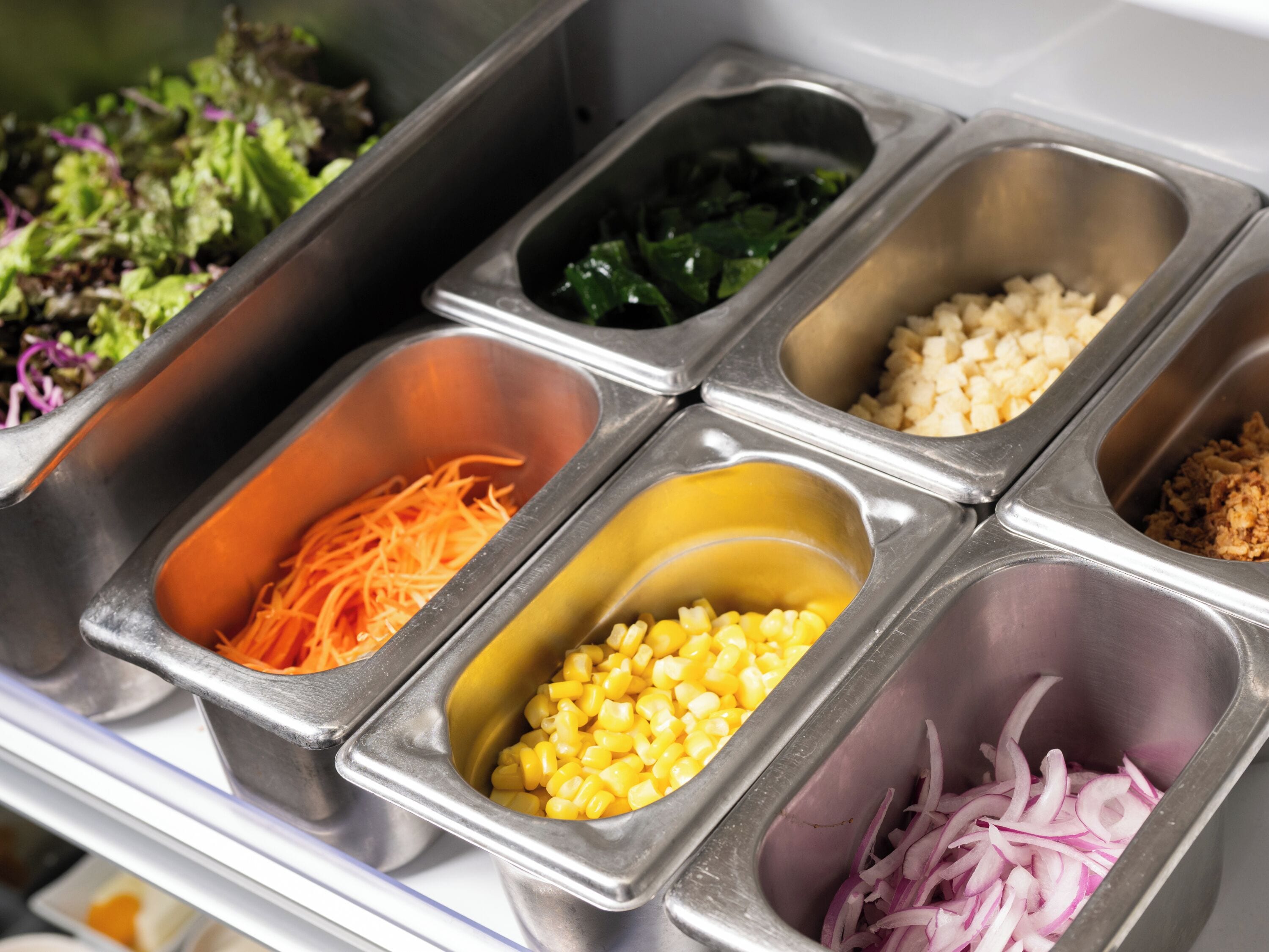 A buffet with various food items in separate metal containers.
