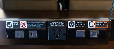 A power outlet with a universal outlet adapter, a desk lamp, and a refrigerator switch.