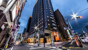 A modern hotel with a prominent entrance, multiple floors, and a parking sign nearby. - Apa Hotel Higashi Shinjuku Kabukicho Tower (Tokyo)