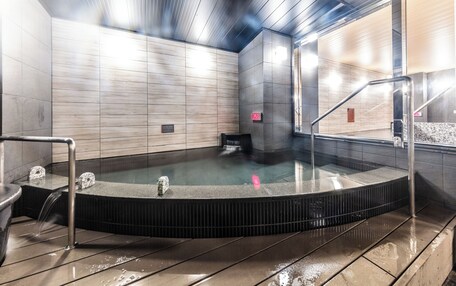 A modern indoor swimming pool with a wooden ceiling and tiled walls.