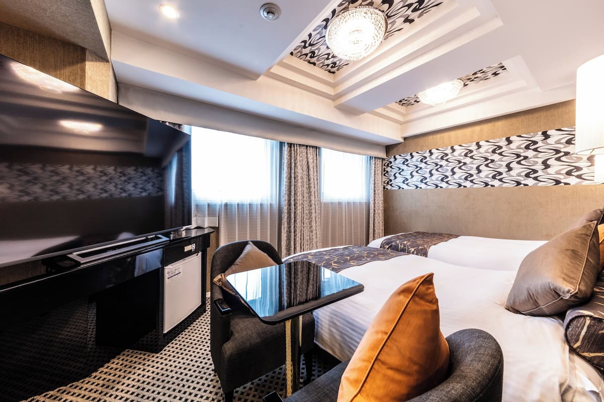 A hotel room with a bed, a desk, a chair, and a small table.