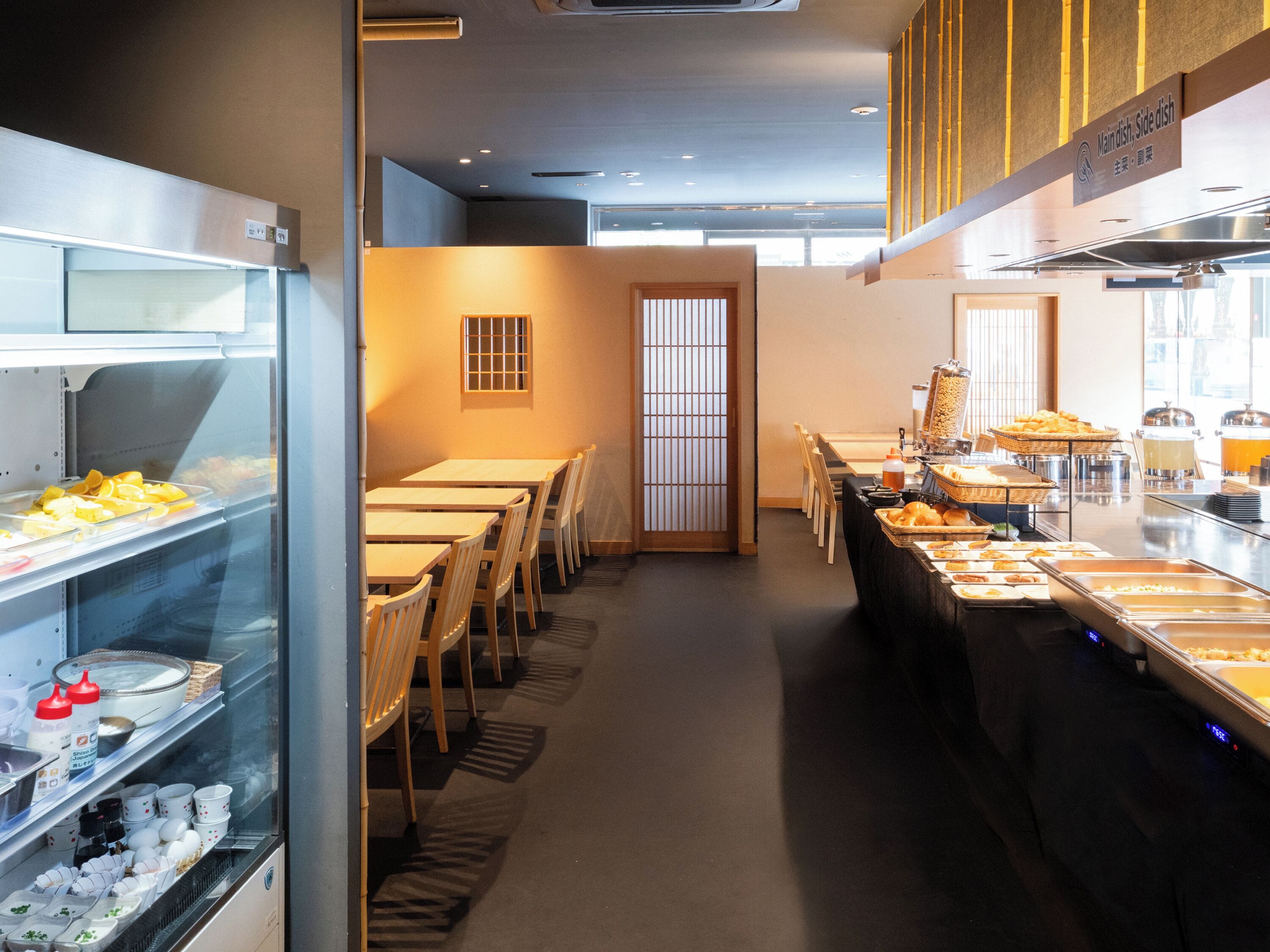 Un espace buffet proposant divers plats, une longue table avec des chaises et un présentoir en verre contenant des condiments.