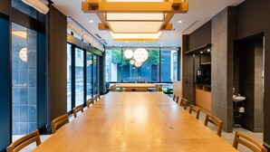 A conference room with a long wooden table and chairs, large windows, and a modern ceiling design. - HOTEL Kazusaya (Tokyo)