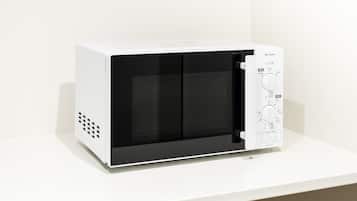 A white microwave with a black interior, a control panel with a dial, and ventilation holes on the left side.