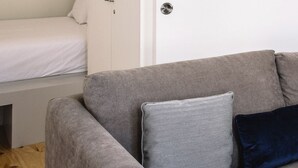 A room with a grey sofa, a white wardrobe, and a bed with white bedding. -  ORM - 3 C´s Apartments (Porto)