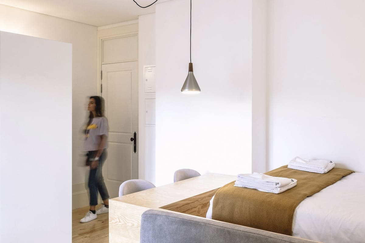 Una habitación de hotel moderna con una cama, una mesa de comedor y una lámpara colgante.