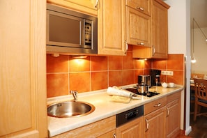 A kitchen with wooden cabinets, a stainless steel sink, a microwave, and a coffee maker.