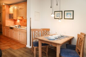 Une cuisine avec des meubles de rangement en bois, un four à micro-ondes et une table à manger avec des chaises.