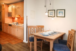 A modern kitchen with wooden cabinets, a microwave, and a dining area with a table set for two.