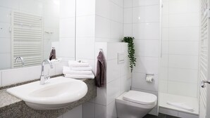 Et moderne badeværelse med vask, toilet og bruser.