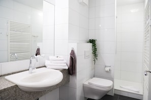 A modern bathroom with a sink, toilet, and shower.