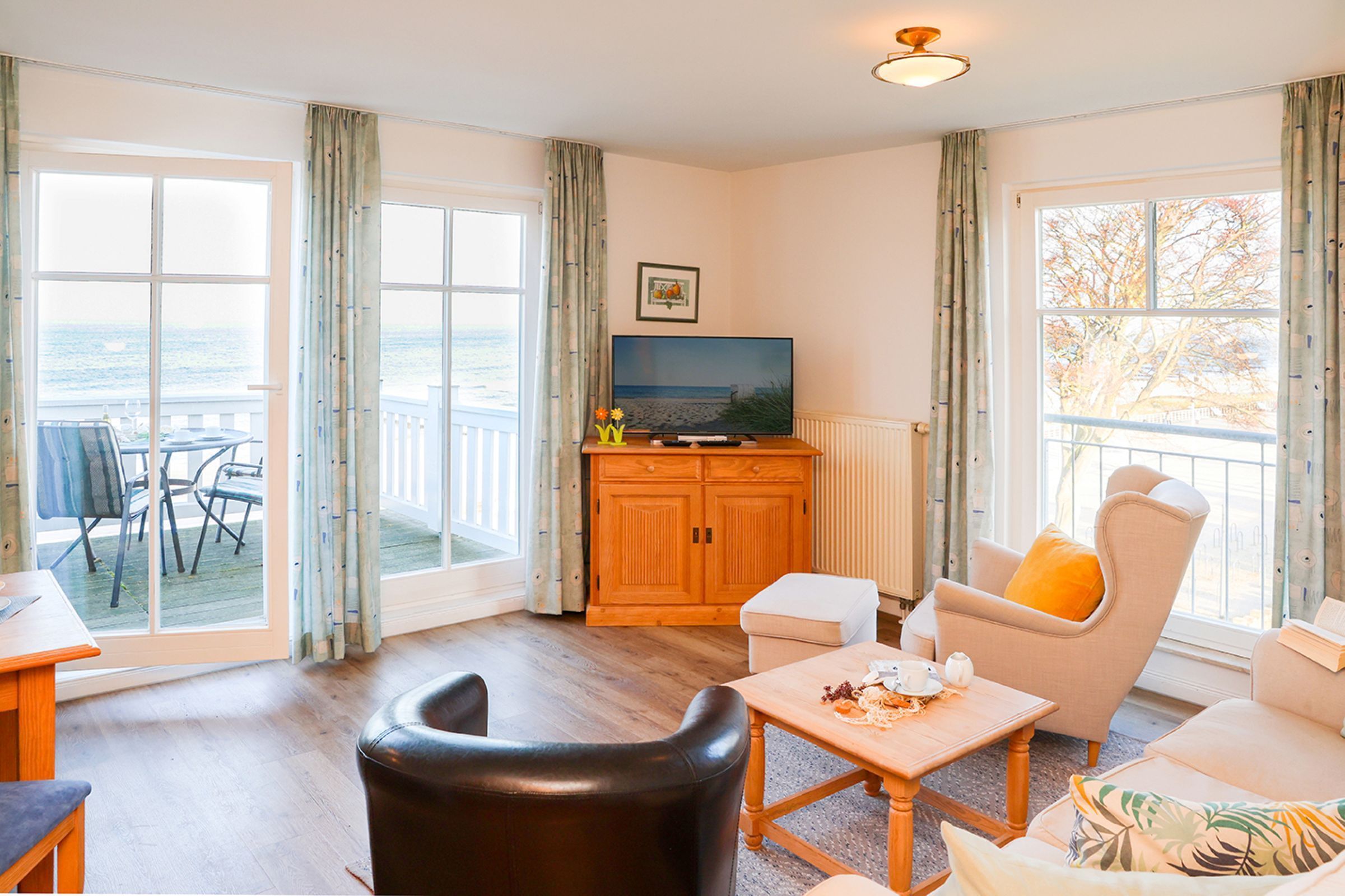 Sala de estar con televisor, asientos y vista al mar.