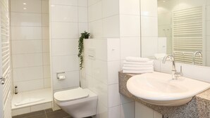 Un baño moderno con inodoro, lavamanos y zona de ducha.