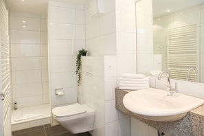 Un baño moderno con inodoro, lavamanos y zona de ducha.