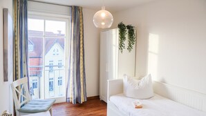 Un dormitorio con cama, escritorio y ventana con cortinas.