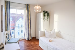 Un dormitorio con cama, escritorio y ventana con cortinas.