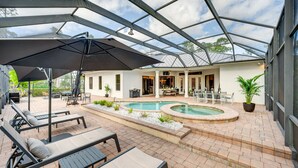 A covered outdoor area with a pool, lounge chairs, and a patio table. - 7 Mi to Great Wolf Lodge Water Park: Luxury House (Naples)