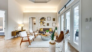 A spacious living room with a sofa, chairs, a coffee table, and a large window. - 7 Mi to Great Wolf Lodge Water Park: Luxury House (Naples)