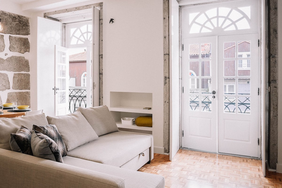 A living room with a beige sofa, a stone wall, and a white door with glass panels.