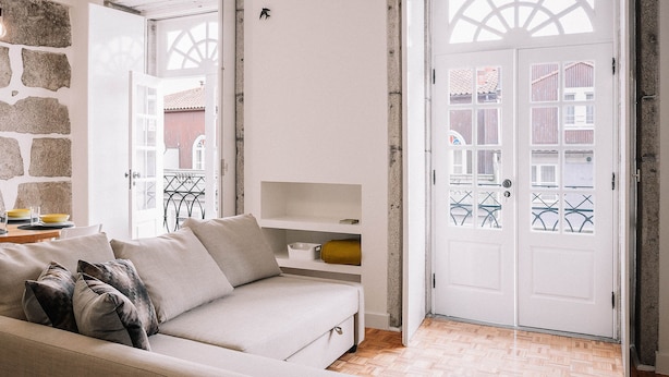 A living room with a beige sofa, a stone wall, and a white door with glass panels.