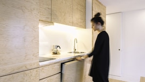 A modern kitchen with wooden cabinetry, a stainless steel sink, and a kettle on the countertop.