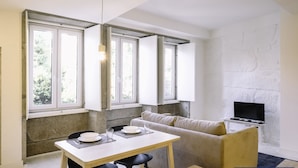 A modern living space with a dining area, sofa, and TV.