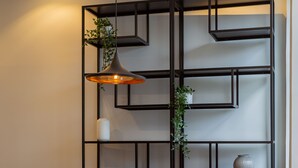 A modern living room with a wooden dining table, grey upholstered sofa, and black metal shelving unit. - ORM - Bolhao Apartments (Porto)