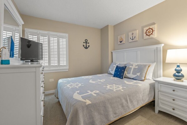 Un dormitorio con cama, cómoda, televisor y decoración náutica.