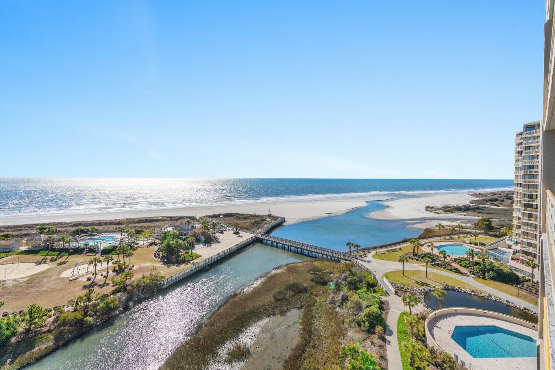 A coastal resort with a beach, a river, and a bridge connecting different areas.