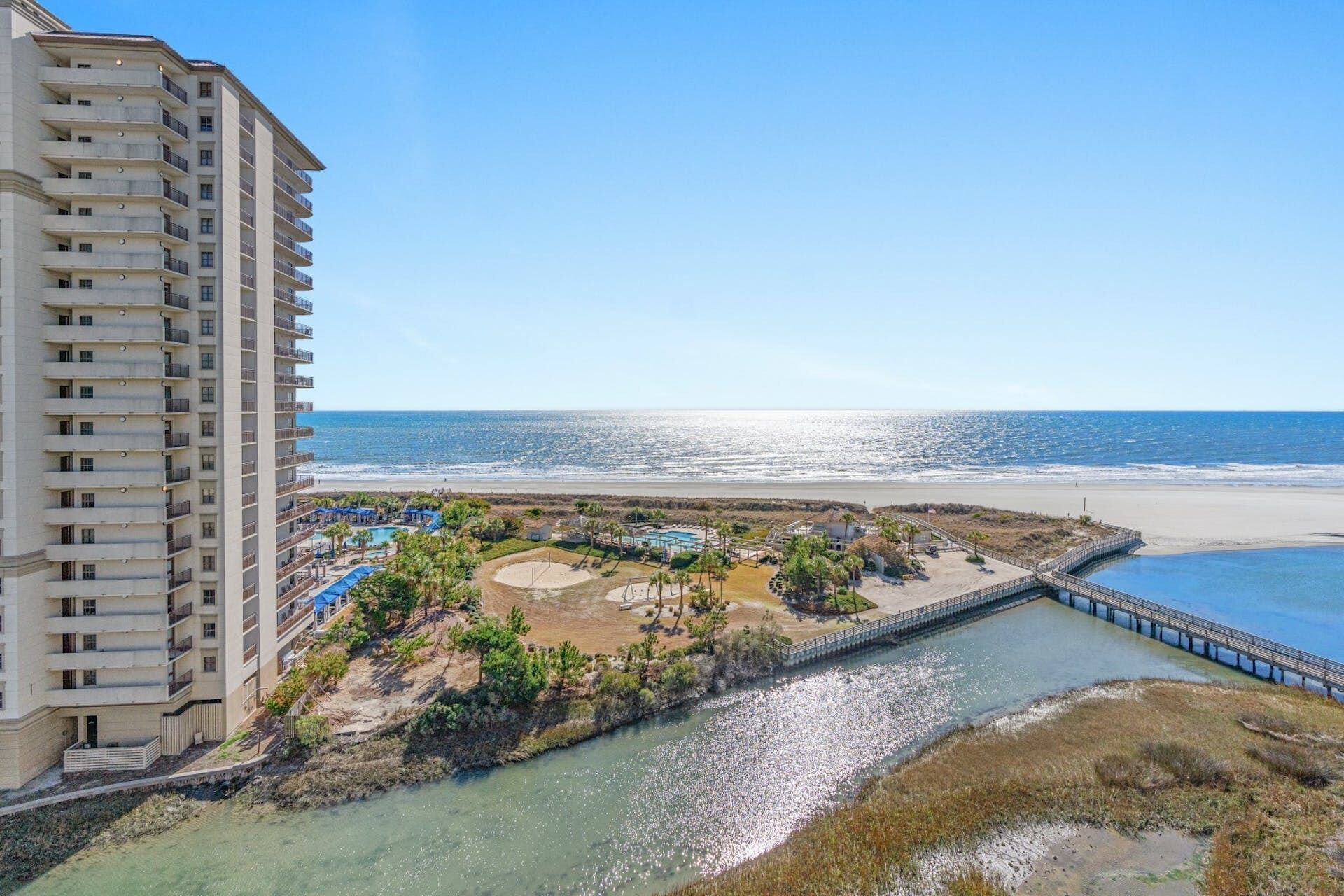 Een hoog hotel met uitzicht op het strand en een klein waterlichaam.