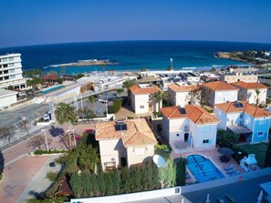 A coastal residential area with houses, a swimming pool, and a view of the sea. - Villa Oforo Selene - Stunning 4 Bedroom Villa - By Fig Tree Bay Beach - Sea View (Protaras)