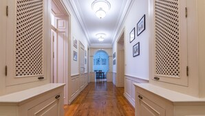 A hallway with wooden floors, white walls, and doors with louvered panels. - Victus Apartamenty - Anda (Sopot)