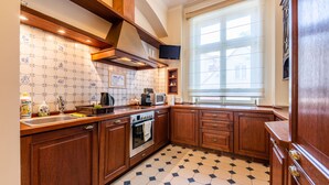 A kitchen with wooden cabinets, a stainless steel oven, a microwave, and a tiled backsplash. - Victus Apartamenty - Anda (Sopot)