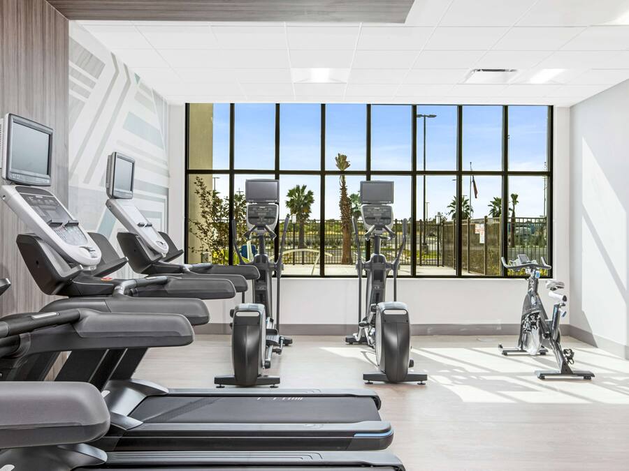 A modern gym with treadmills, stationary bikes, and elliptical machines.